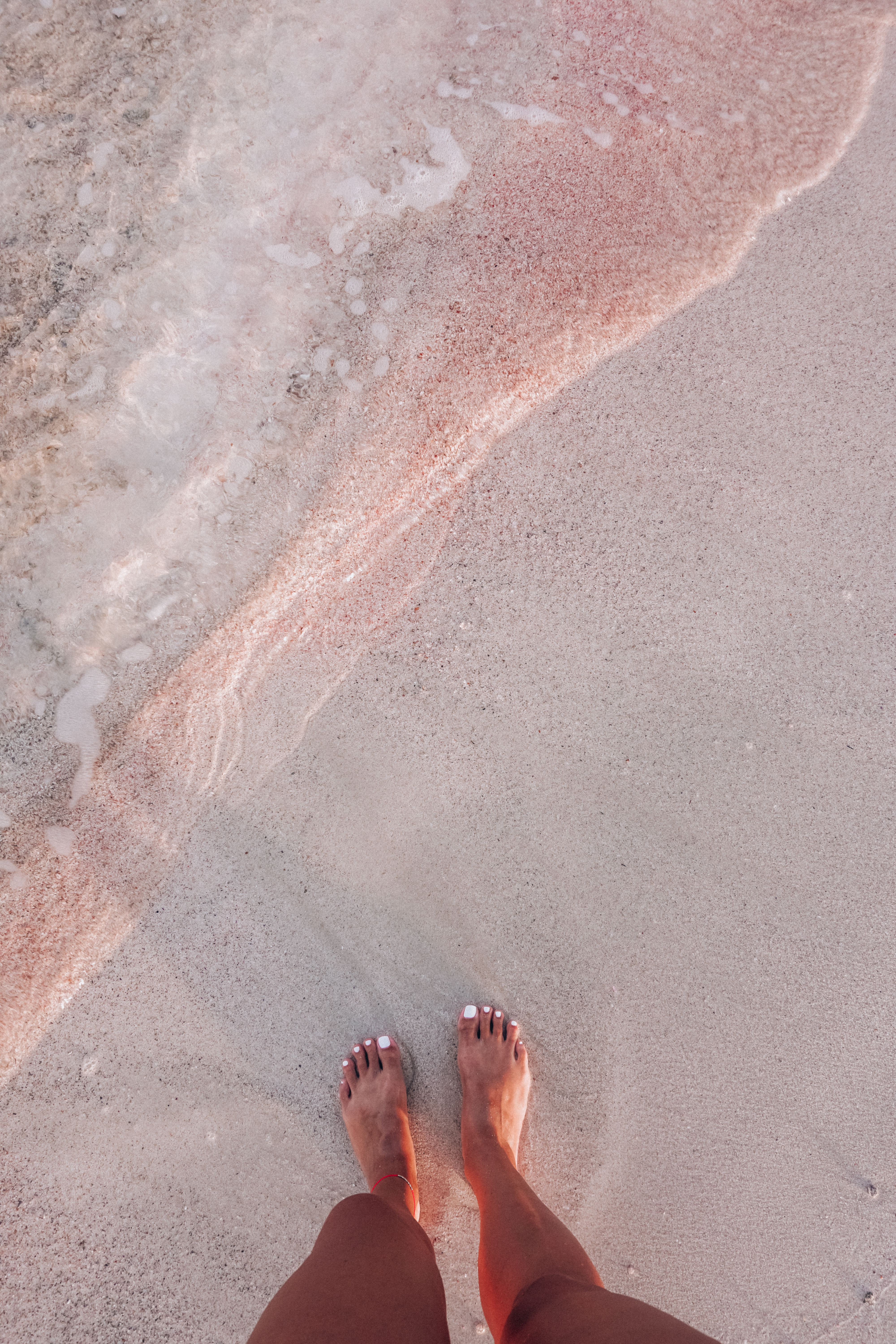 A girl feet on the iconic pink sand of Elafonisi Beach on Crete Island in Greece