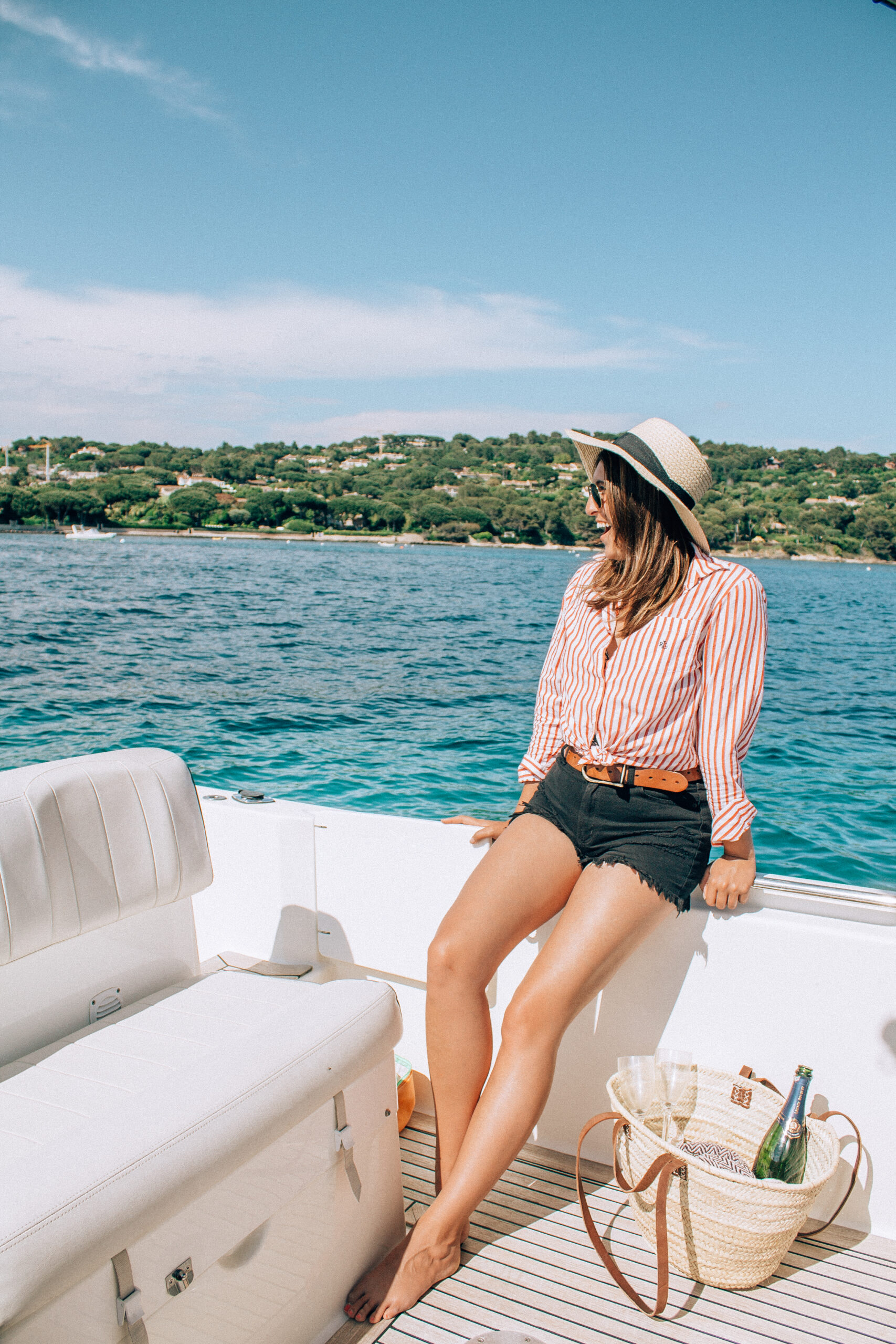 A lady on a boat in Saint Tropez looks happy and exciting while sailing around the blue waters and sips champaign