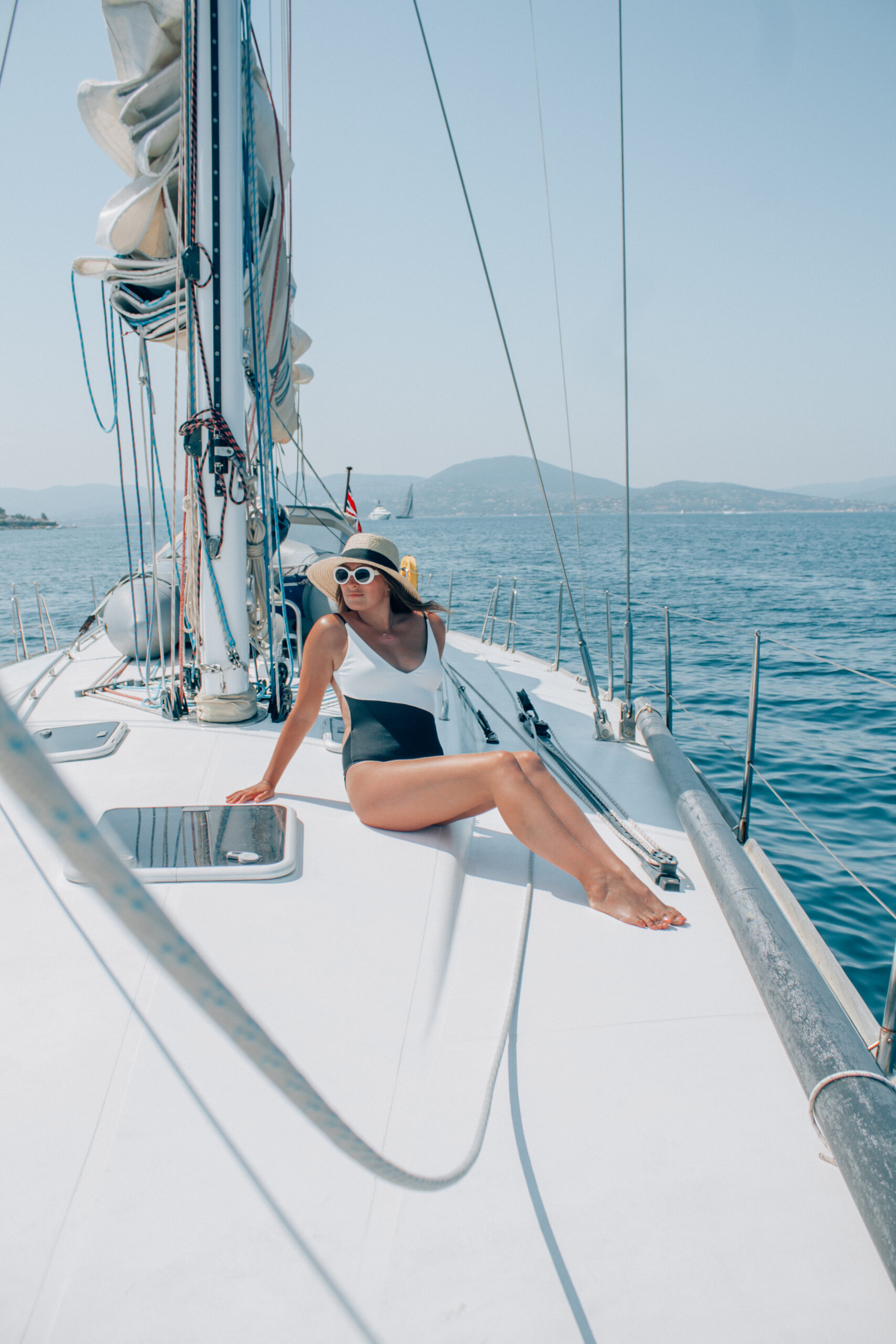 A lady in a bathing suit sits on a sail boat while cruising along the French Riveria, a must-do while visiting France. 