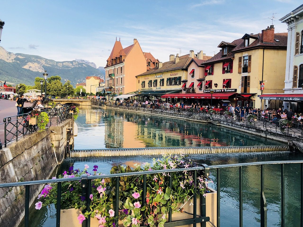 A canal in Lake Annecy's Old Town with colourful houses and flower boxes decorating the narrow alleyways in France