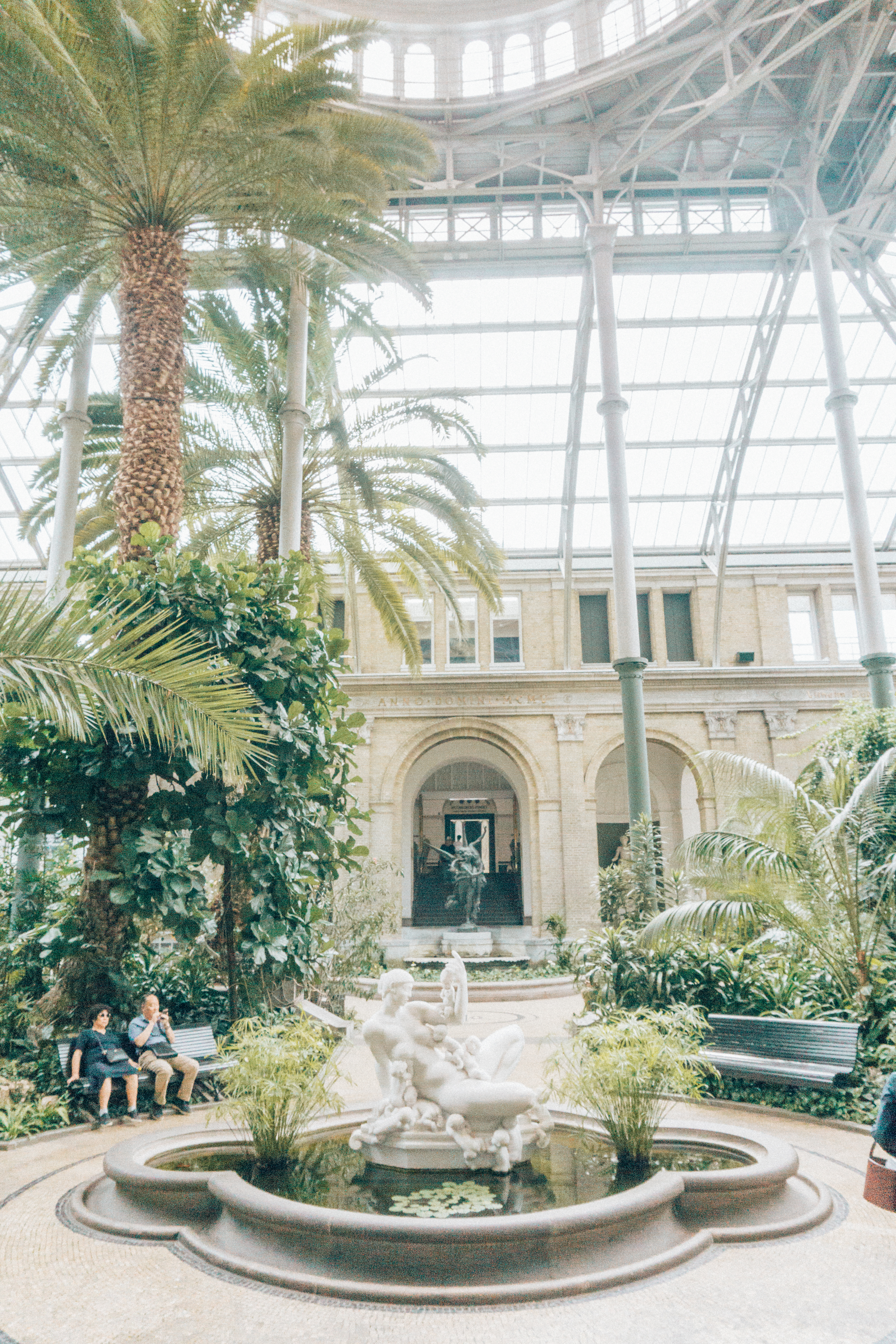The great atrium in Copenhagen's Glyptotek with live plants, palm trees, sculptures and fountains.