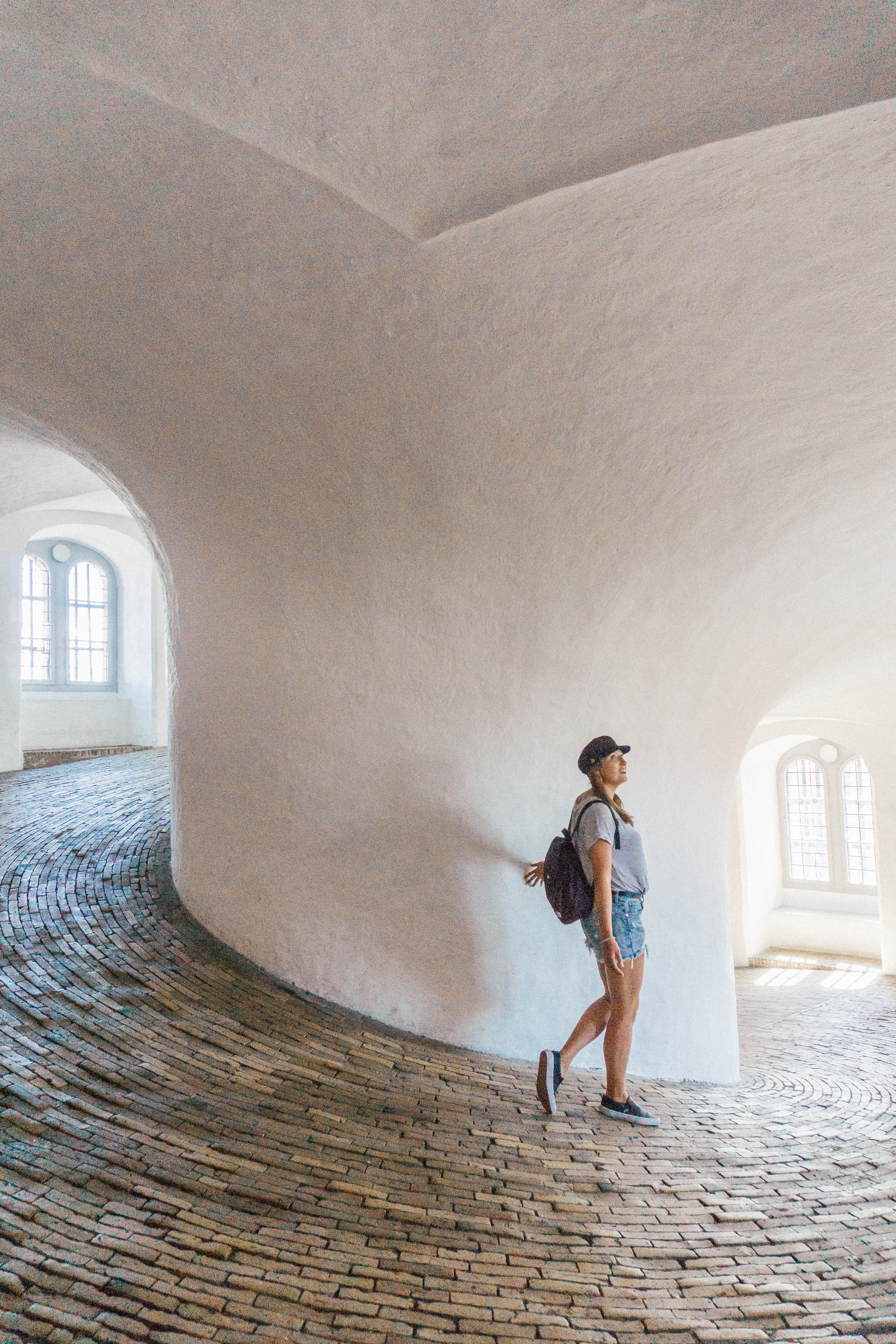 A girl with a hat and backpack walks through the spiral ramp in the Round House in Copenhagen