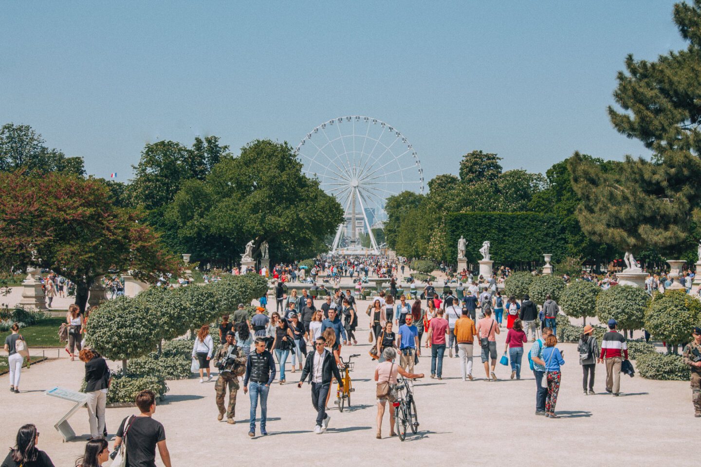 Tourists walk through central Paris, France in the spring months with the ferris wheel in the distance