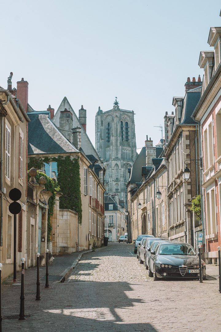 The quaint streets of Bourges, France with the gothic cathedral at the end of the road.