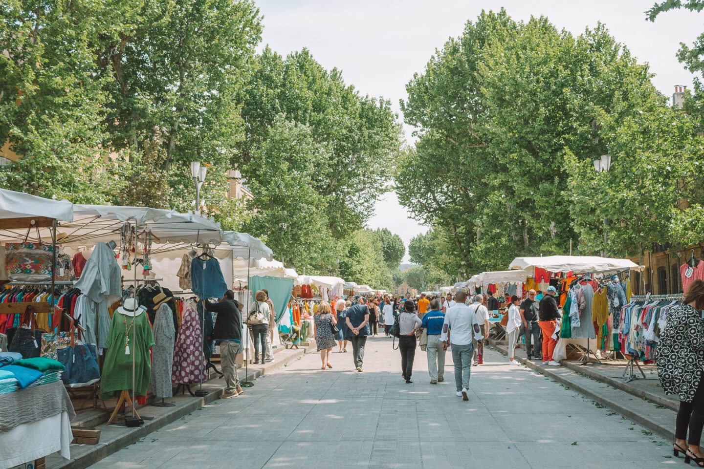 Visitors pass through the outdoor market under the trees of Aix-en-Provence, France