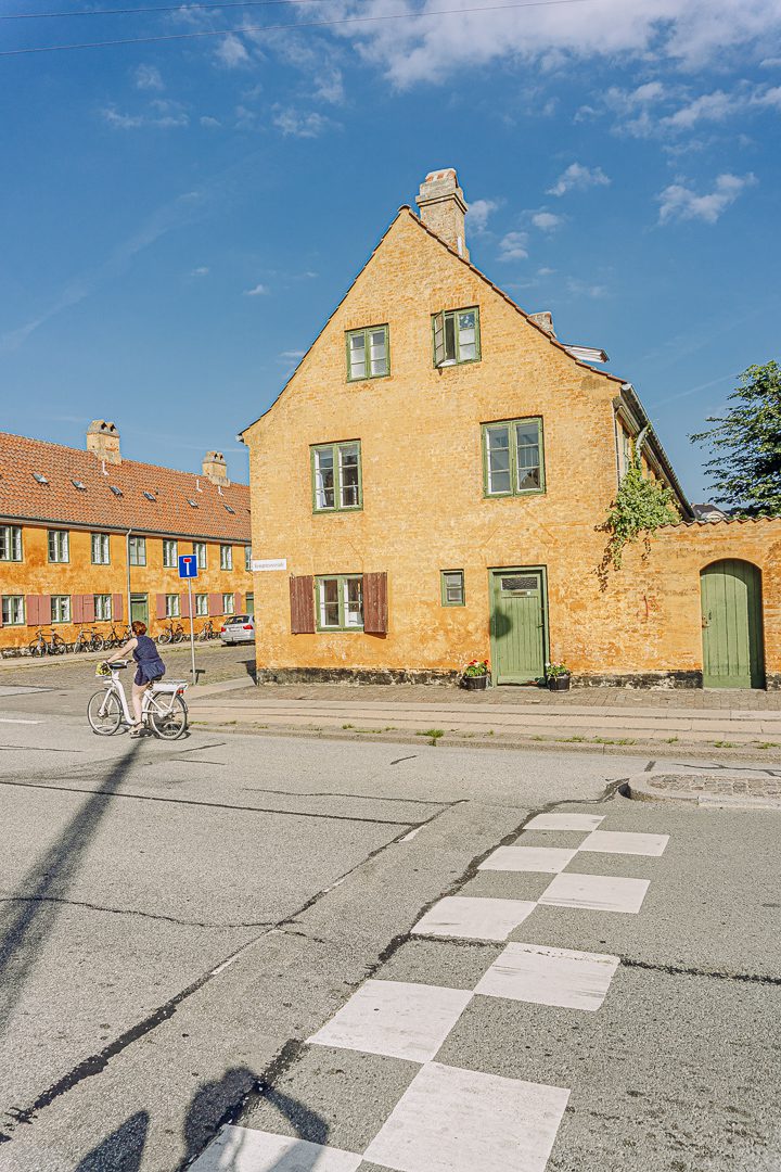 A lady bikes by the old historic yellow brick Nyboder Houses in Copenhagen