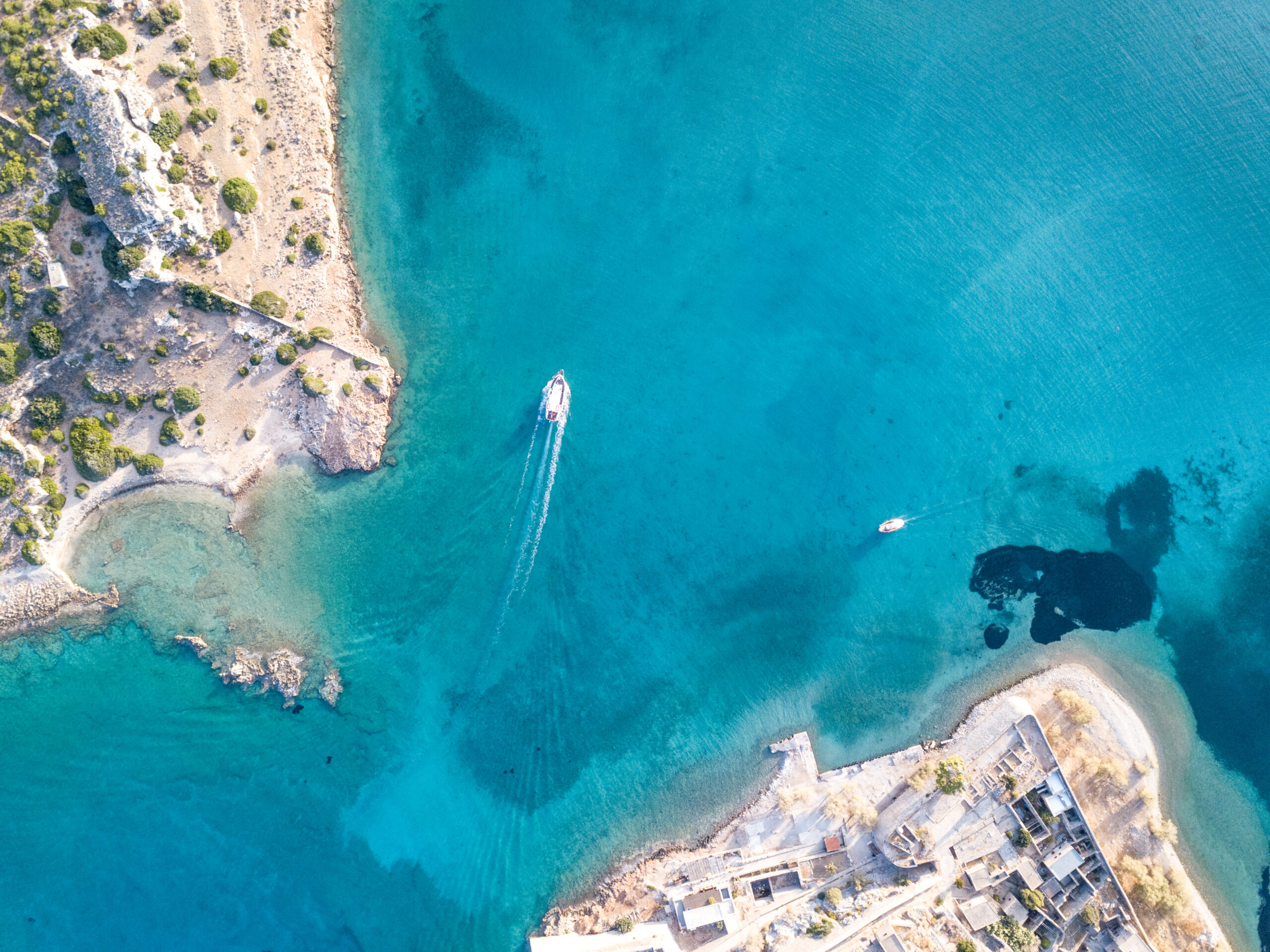 A boat sails over the bright blue waters of Crete during a sailing trip from Heraklion to Dia island. One of the top things to do in Crete!