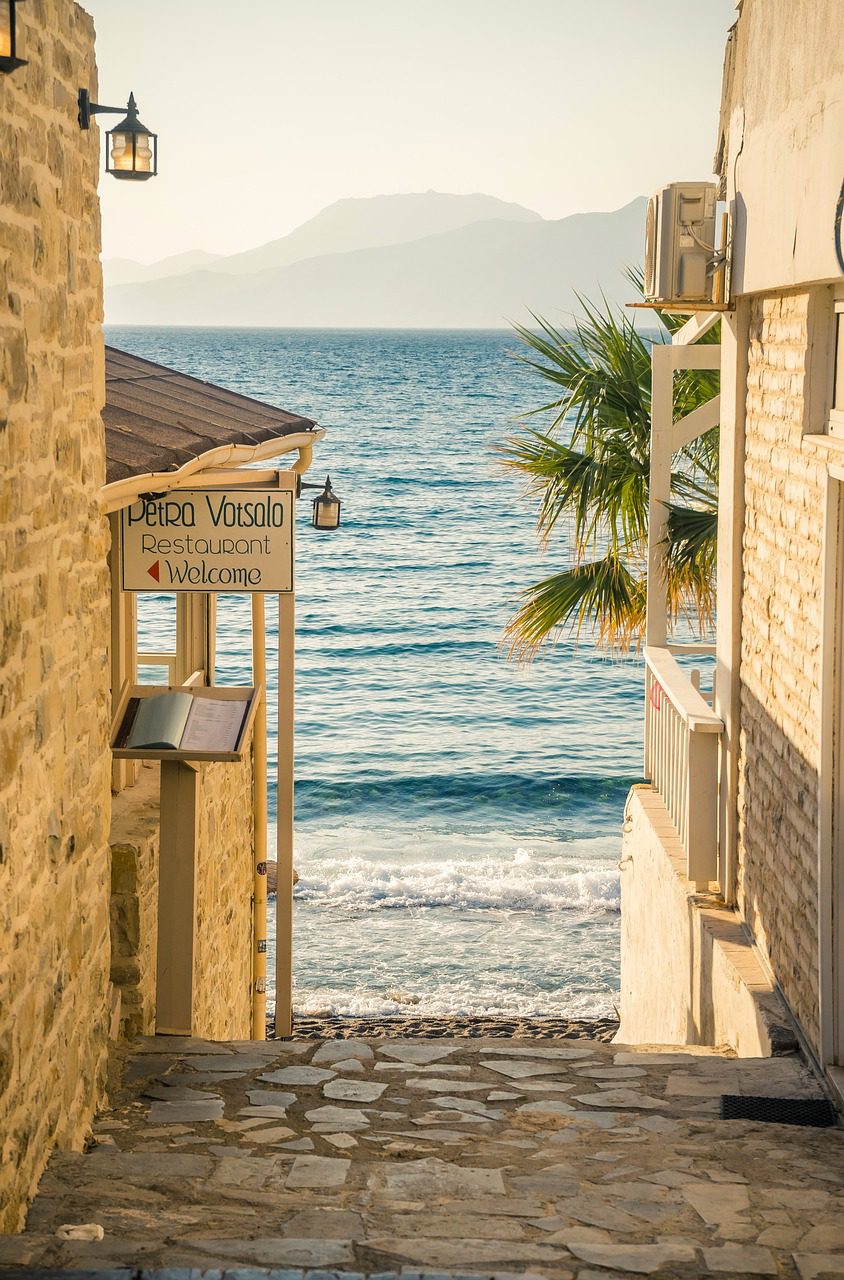 A Tavern sign in Matala, Crete at golden hour, with the ocean and mountains in the background. 