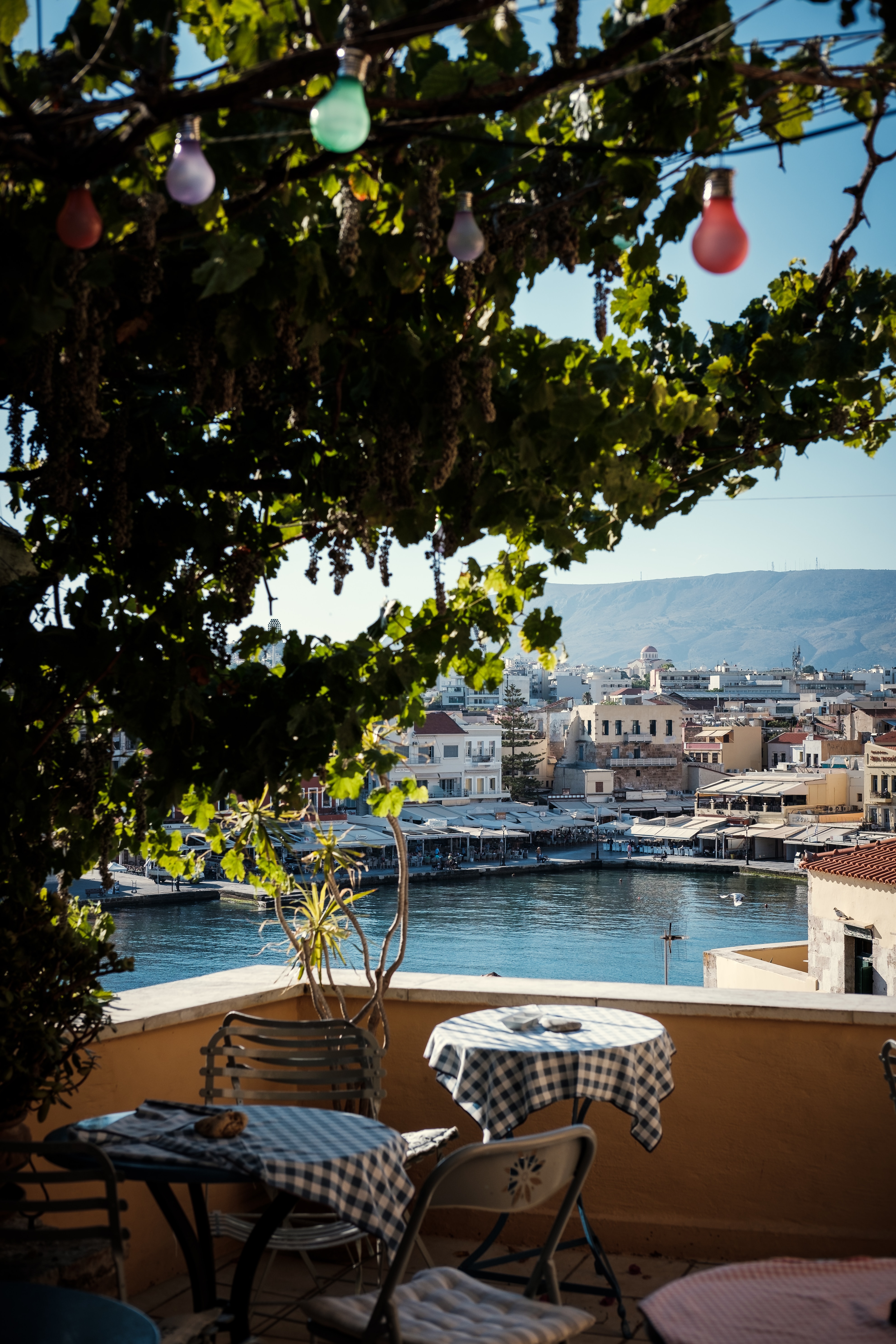 A tranquil patio with table and chairs looks over the waterfront old town in Chania, Crete.
