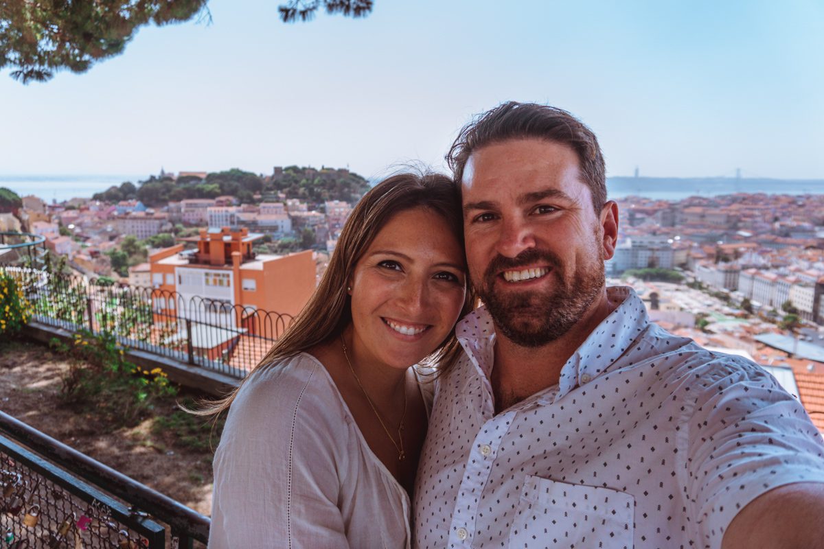 A couple soaks in the beautiful views of Miradouro da Senhora do Monte viewpoint in Lisbon Portugal 