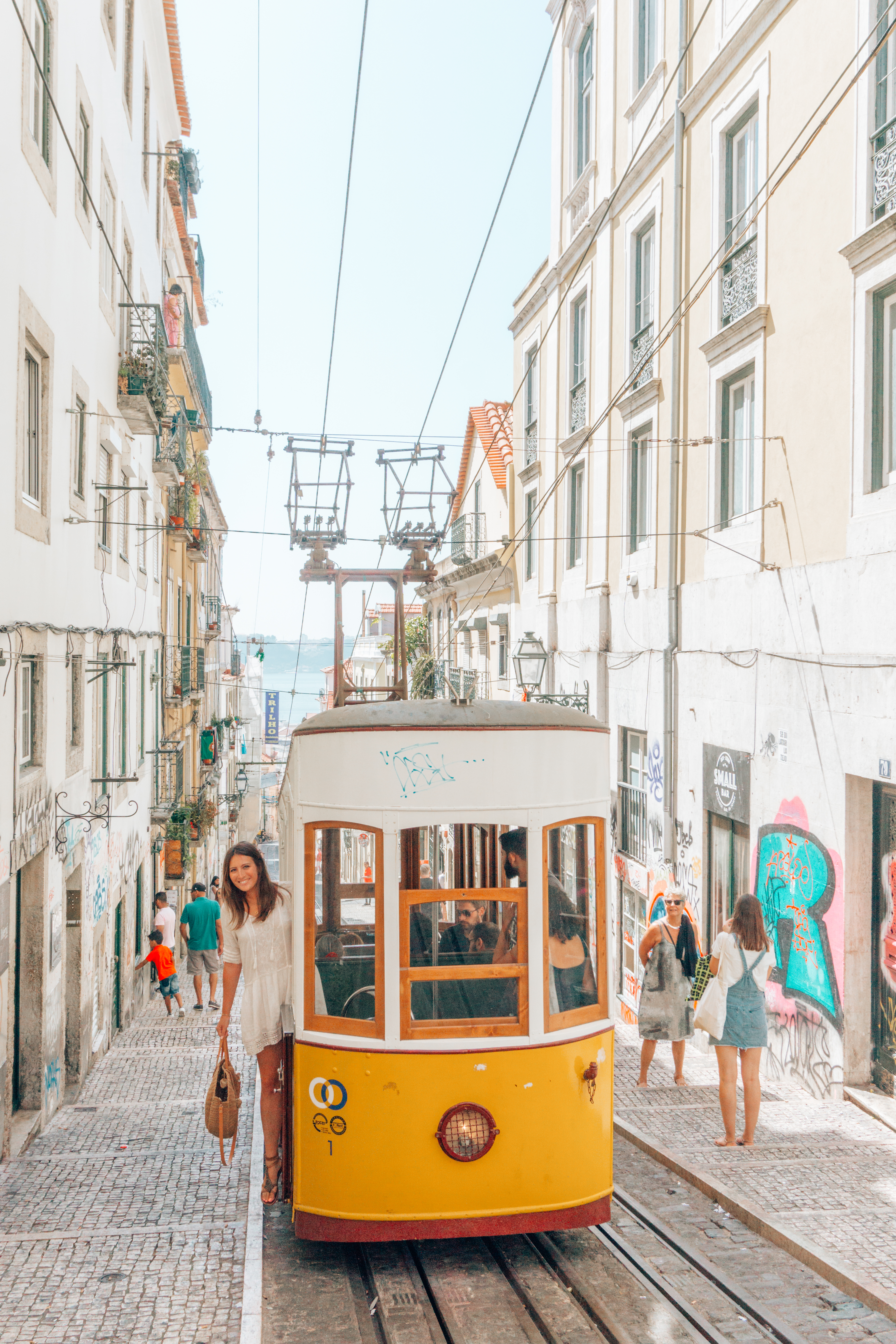 A girl hangs off of Tram 28 - a must do on your 3 days in Lisbon Itinerary