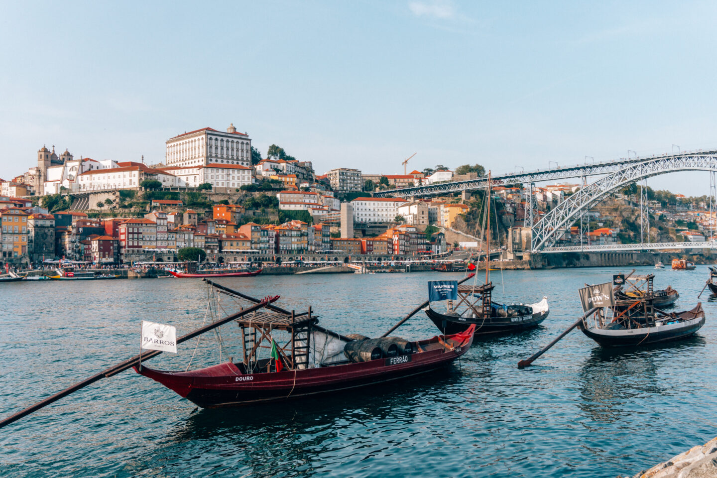 Traditional boats and the Dom Luís I Bridge over the Douro River in Porto, Portugal. The Ultimate Porto Itinerary for First-time Visitors