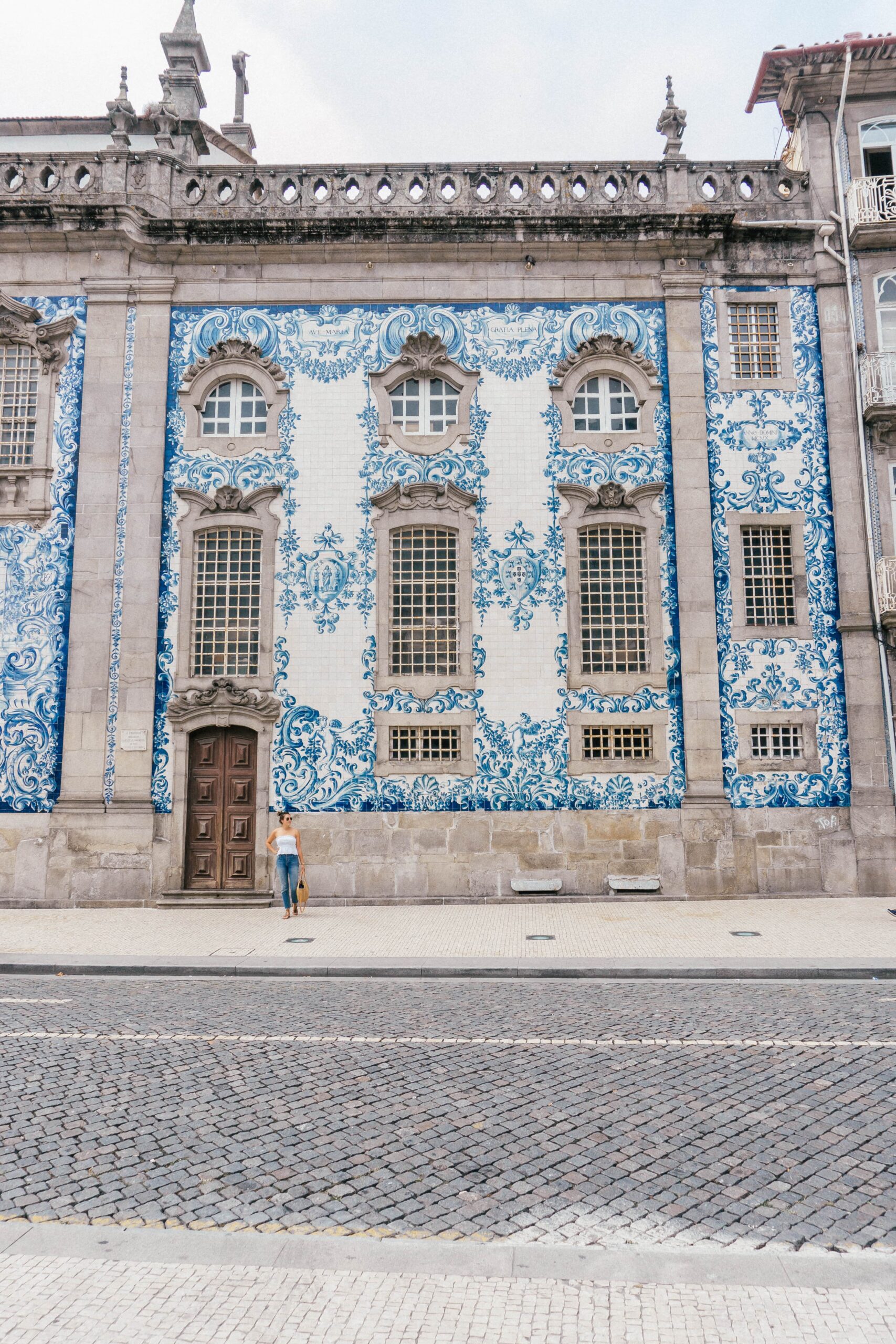 A girl stands in front of the famous blue azulejo tiled Igreja do Carmo Church, in Porto Portugal