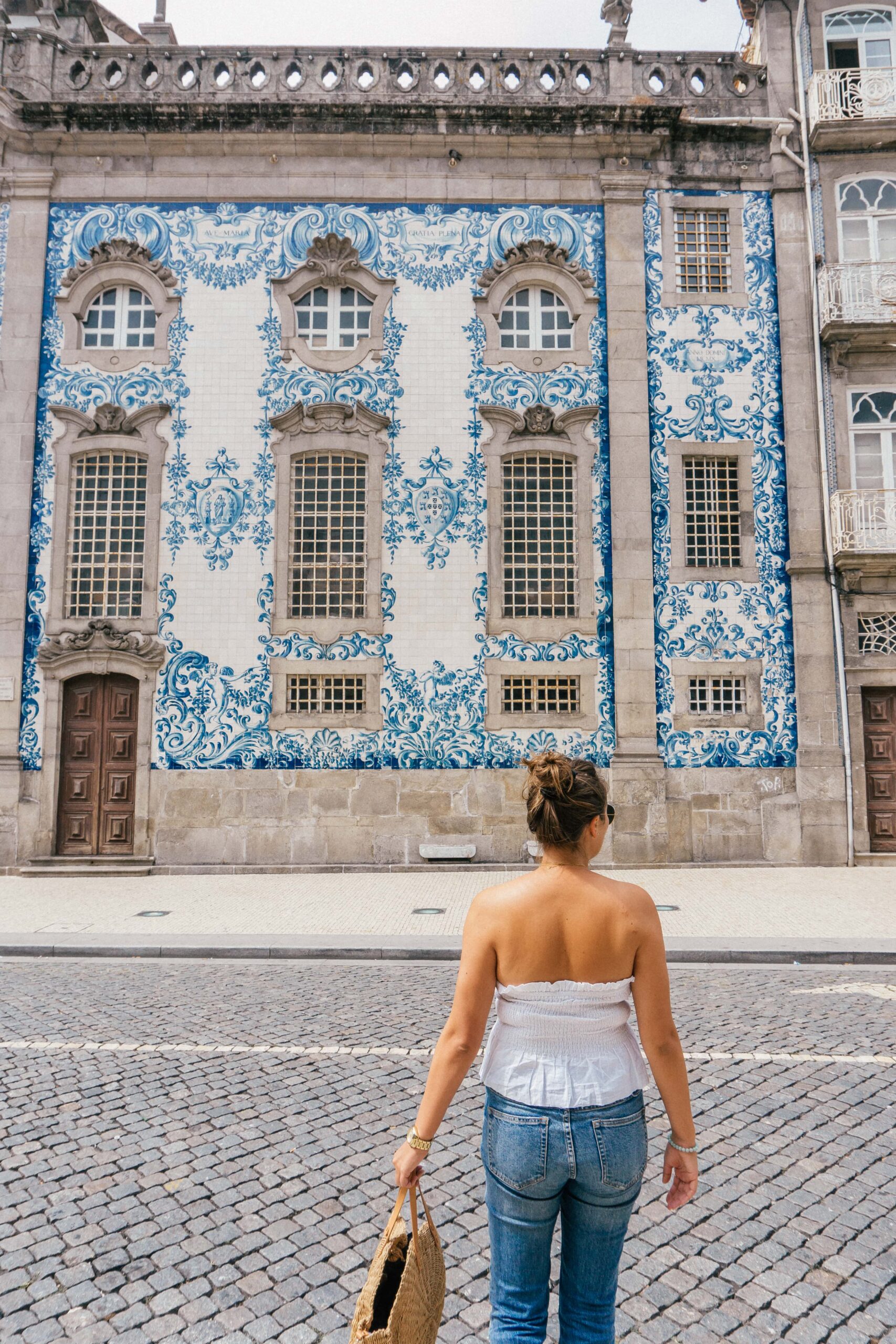 A girl walks across the street to the beautifully azulejo tiled Igreja do Carmo Church, in Porto Portugal.