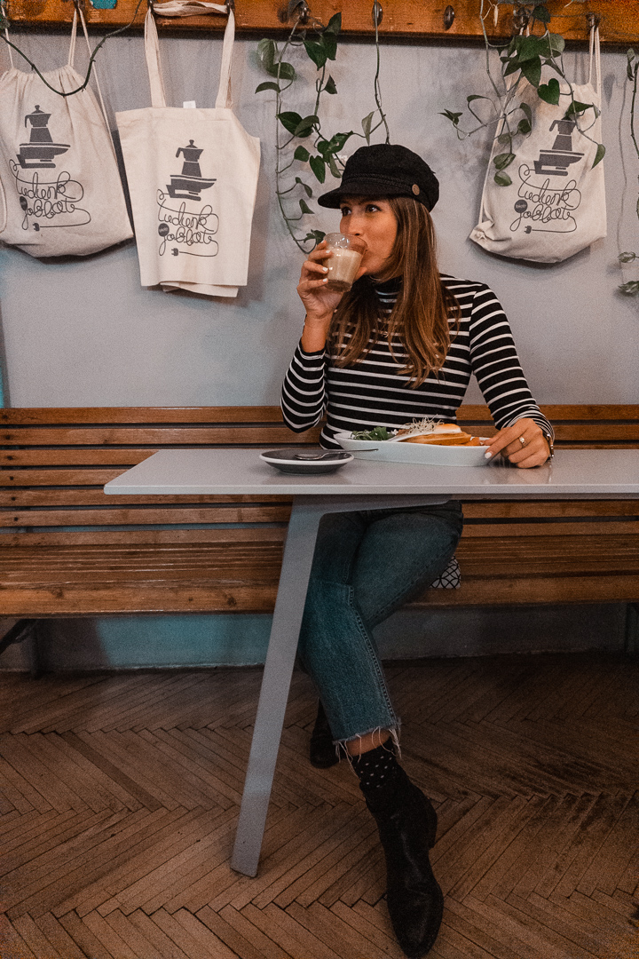 A girl in a striped shirt sips a cafe latte and enjoys breakfast in Fekete Cafe in Budapest, Hungary