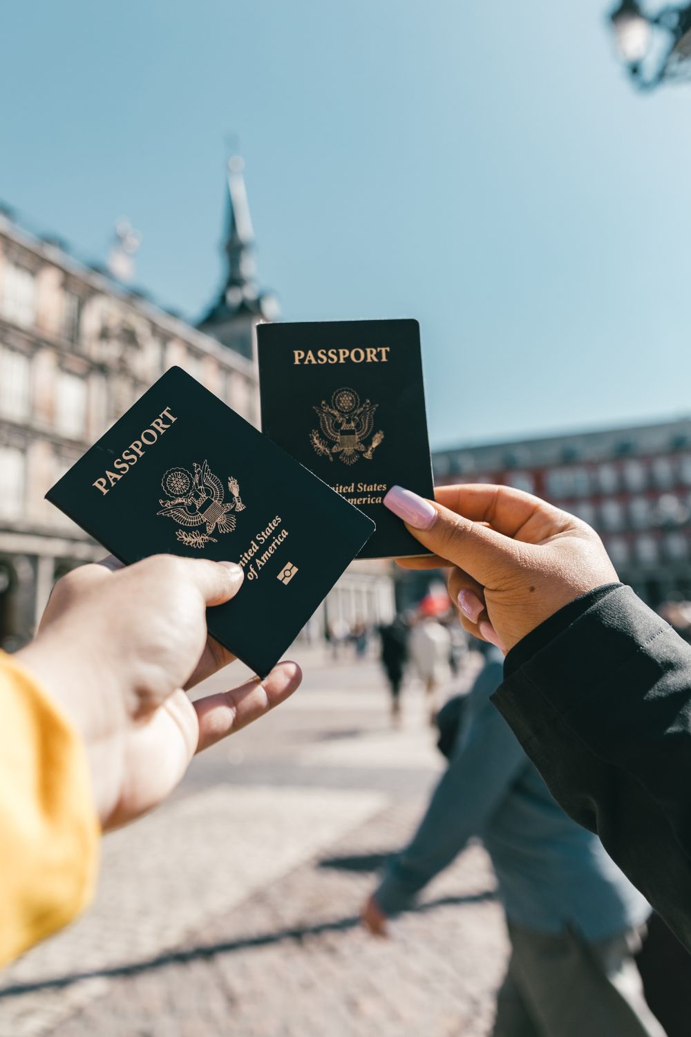 Two people hold up their US passports in Europe. One of the most important things for your carry on packing list is your passport!