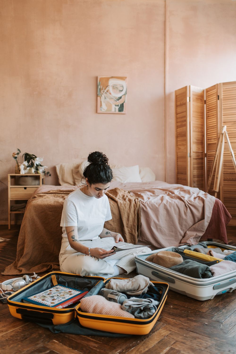 A girl sit on the floor of her pink room and reads her carry on packing list while preparing for her next big trip. 