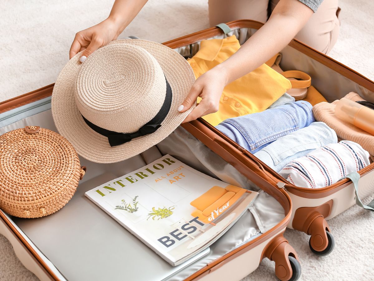 A girl packs her sun hat in her carry on suitcase for her sunny trip away