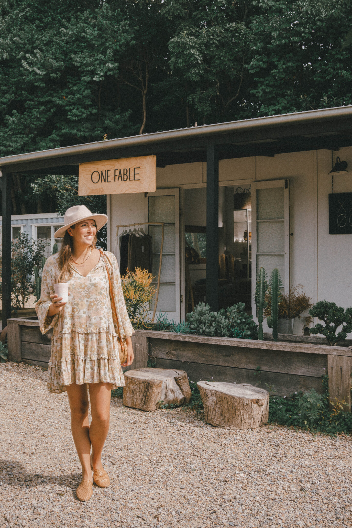 A women holds a cup of coffee while strolling in front of boutique shops in Byron Bay Australia. 