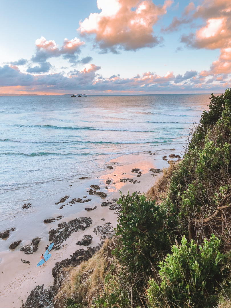 Two surfers heading out for a sunset surf at Wategos beach, in Byron Bay.