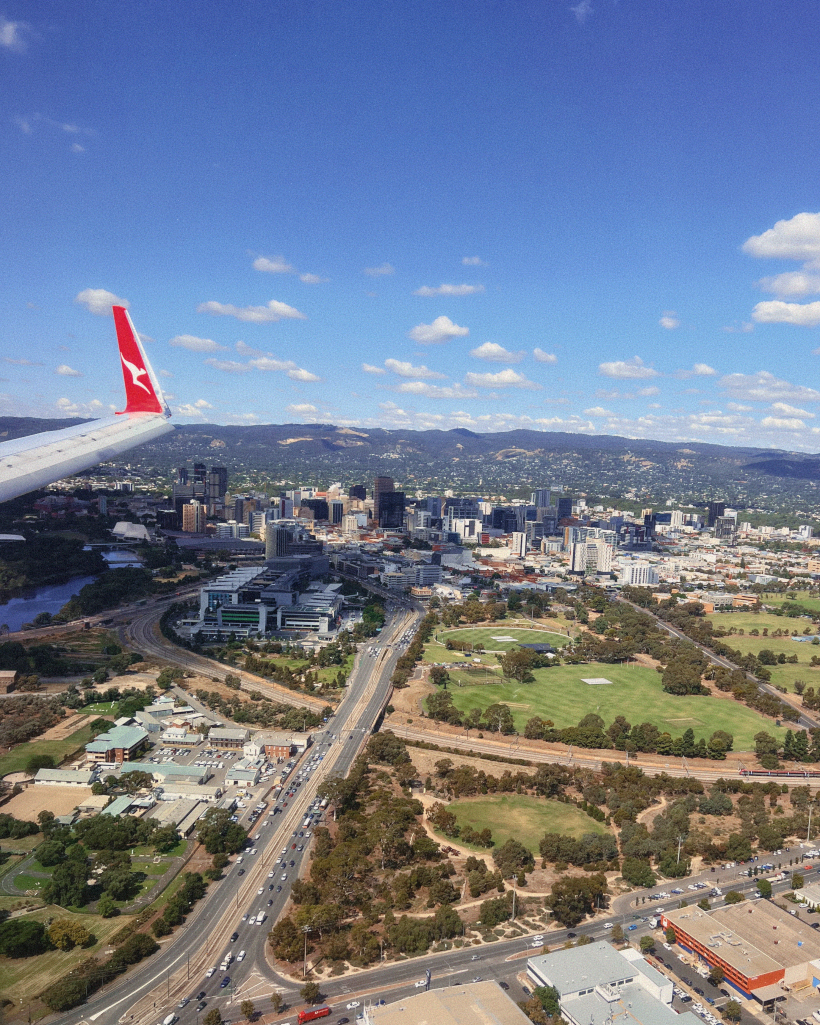 A Qantas plane wing flying over Adelaide City