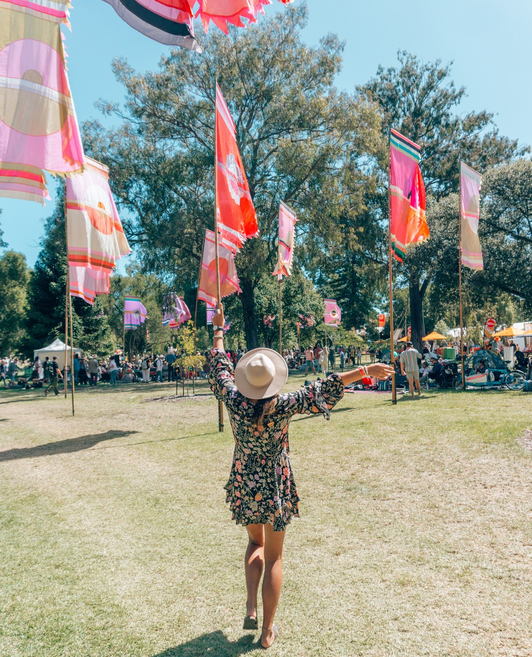 A girl in a dress dancing under colourful flags during the WOMAD music festival that happens every March – fun things to do in Adelaide