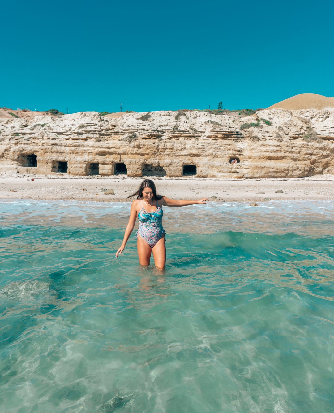 A girl walks into the ocean at Port Willunga Beach - day trips from Adelaide 