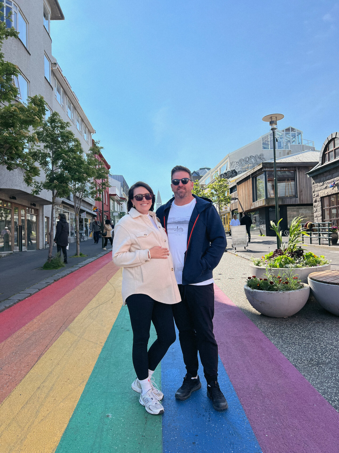 An expecting couple stands on the rainbow road in the middle of Reykjavik, Iceland's capital