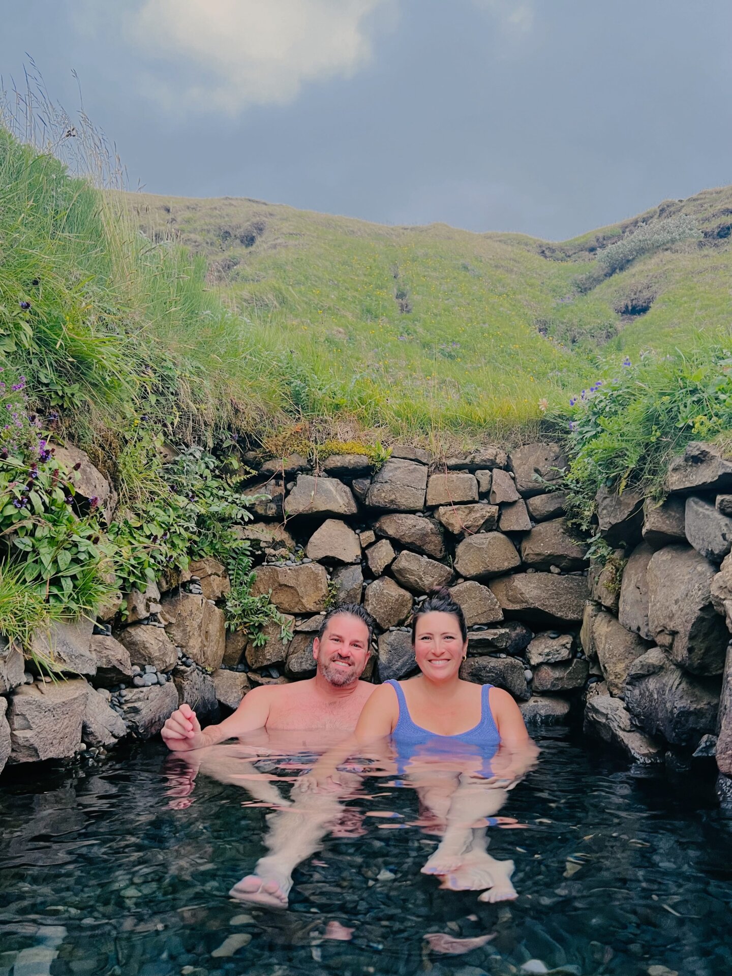A couple relaxing in the Hrunalaug Hot Springs during their 4 days in Iceland Road Trip